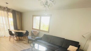 Uma sala de estar moderna com sofá, duas poltronas, mesa de centro e mesa de jantar com cadeiras.