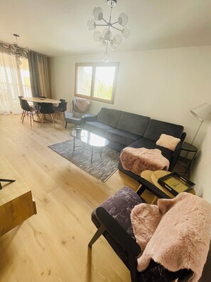 A modern living room with a sofa, two armchairs, a coffee table, and a dining table with chairs. - Paradise in Megève (Megève)