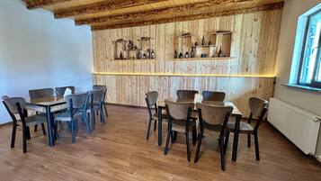 Un interior de madera con una zona de bar, varios arreglos de asientos y un ventanal.