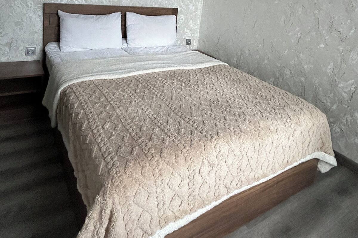 Ein Schlafzimmer mit einem hölzernen Bett, einer strukturierten Wand und einer hängenden Leuchte.