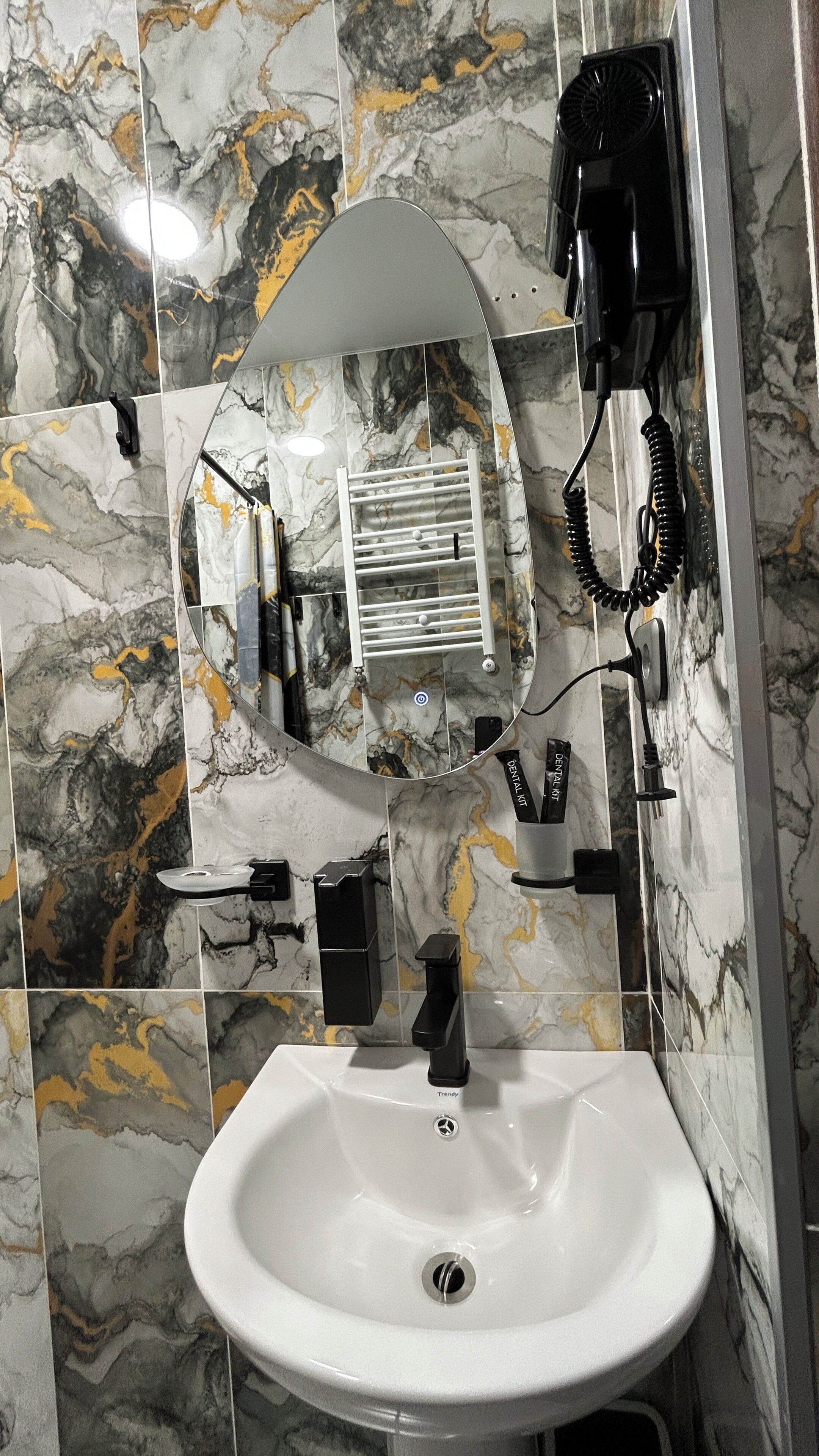 A bathroom with a white sink, a mirror, a towel rack, and a hairdryer.