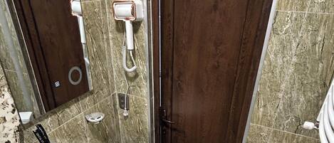 Een badkamer met een marmeren wand, een wastafel, toilet en douche.