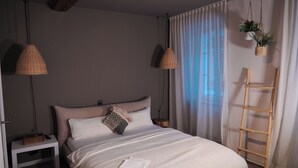 Une chambre à coucher avec un lit, des tables de chevet, une plante suspendue et une échelle en bois.