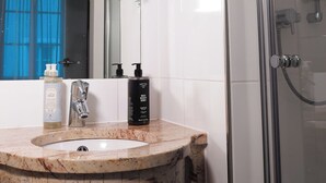 Une salle de bain avec un lavabo en marbre, une douche en verre et une plante suspendue.