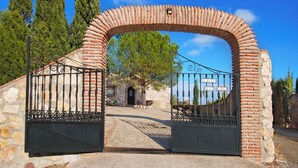 Een bakstenen boogpoort die leidt naar een stenen gebouw met een metalen hek.