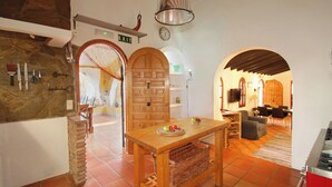 Een keuken met een houten tafel, een stenen muur en een klok aan de wand.