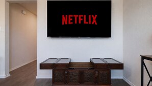 Un saló amb un televisor de pantalla plana fixat a la paret que mostra el logotip de Netflix.