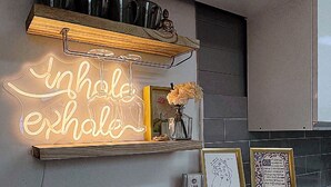 A kitchen with a neon sign, a kettle, a microwave, and a shelf with kitchenware. - House Lotus (Seoul)