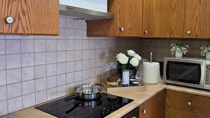 Eine Küche mit Holzausstattung, einem Herd, einer Mikrowelle und einem Kühlschrank.