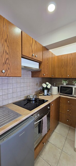 Eine Küche mit Holzausstattung, einem Herd, einer Mikrowelle und einem Kühlschrank.