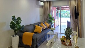 Ein modernes Wohnzimmer mit einer Couch, einem Esstisch und einer Decke mit eingelassener Beleuchtung sowie einem Zierteil.