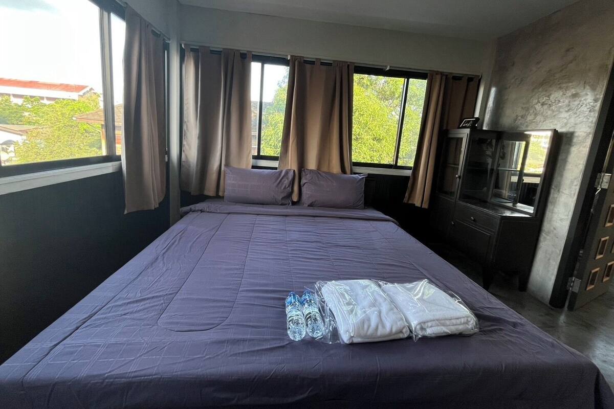 A hotel room with a large bed, a TV, and a window with curtains.