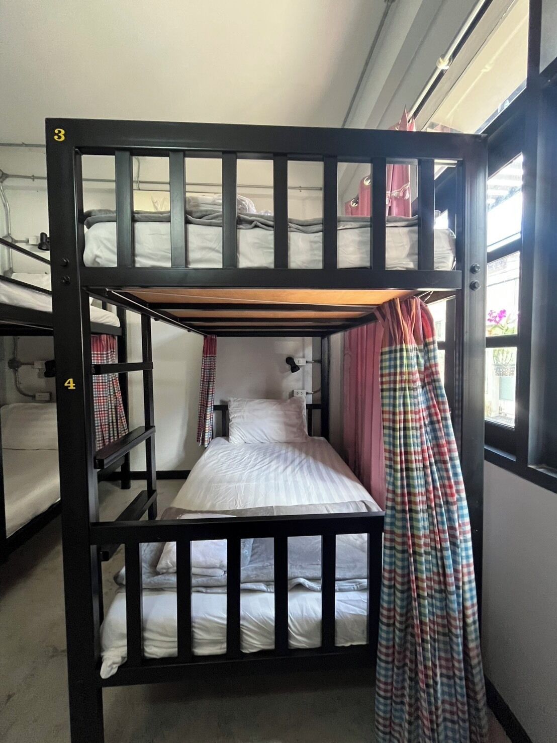 Un letto a castello con due piani, una finestra con tende e una porta ben visibile.