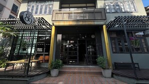 A building with a modern facade, large windows, and a sign indicating a press. - BNK89 Hostel (Bangkok)