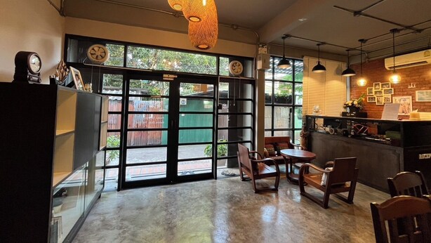 A cafe with a rustic interior, featuring exposed brick walls, a concrete floor, and a mix of wooden and metal furniture. - BNK89 Hostel (Bangkok)