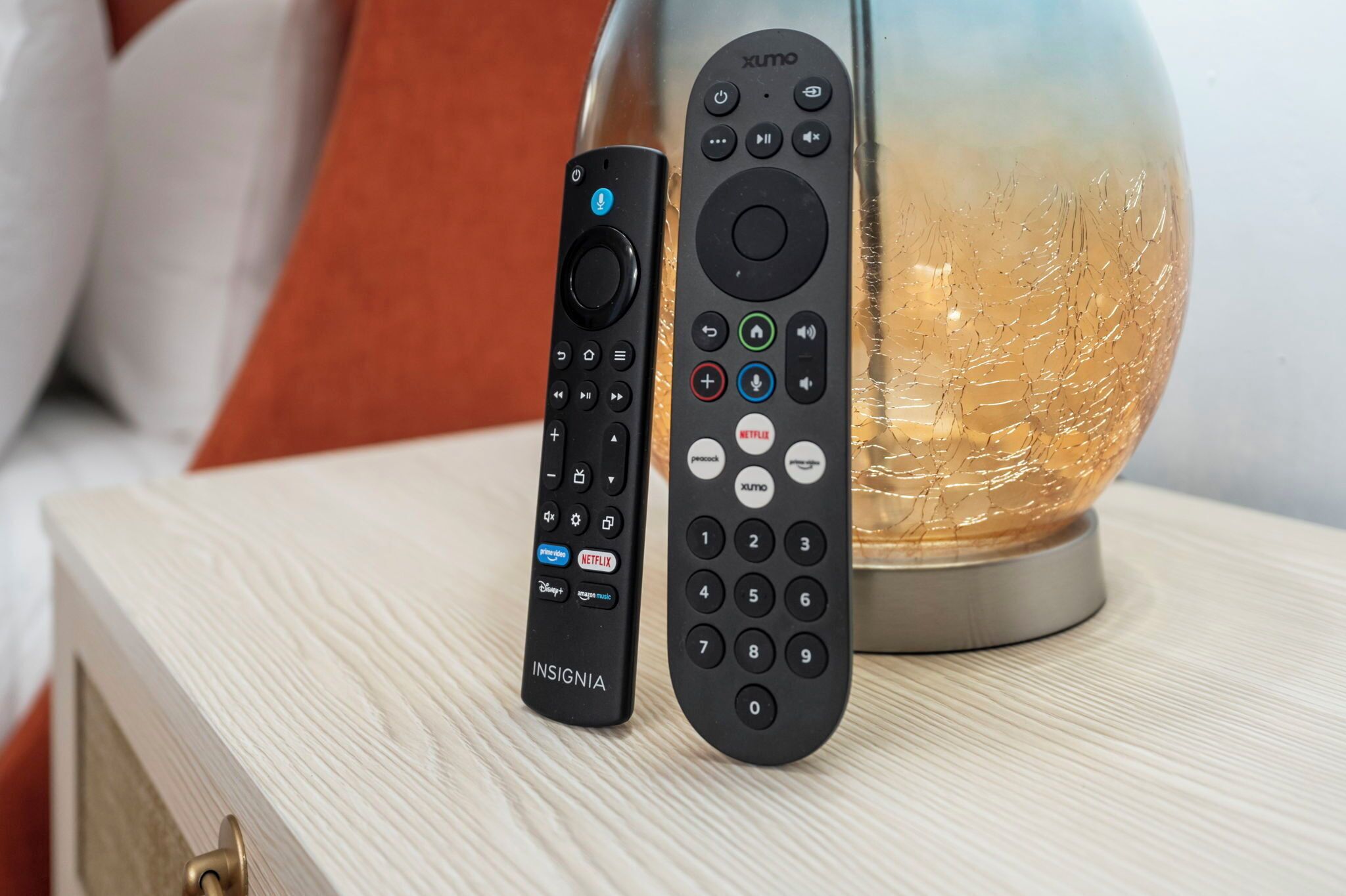 Due telecomandi su una superficie in legno, con una lampada globo decorativa sullo sfondo.