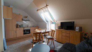 A compact living space with a kitchenette, a dining area, and a seating area with a television. - Vacation apartment Cantnitz, your retreat in the middle of the Feldberg lake district. (Feldberger Seenlandschaft)