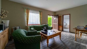 A living room with a sofa, a wooden coffee table, and a television on a cabinet. - Vacation apartment Cantnitz, your retreat in the middle of the Feldberg lake district. (Feldberger Seenlandschaft)