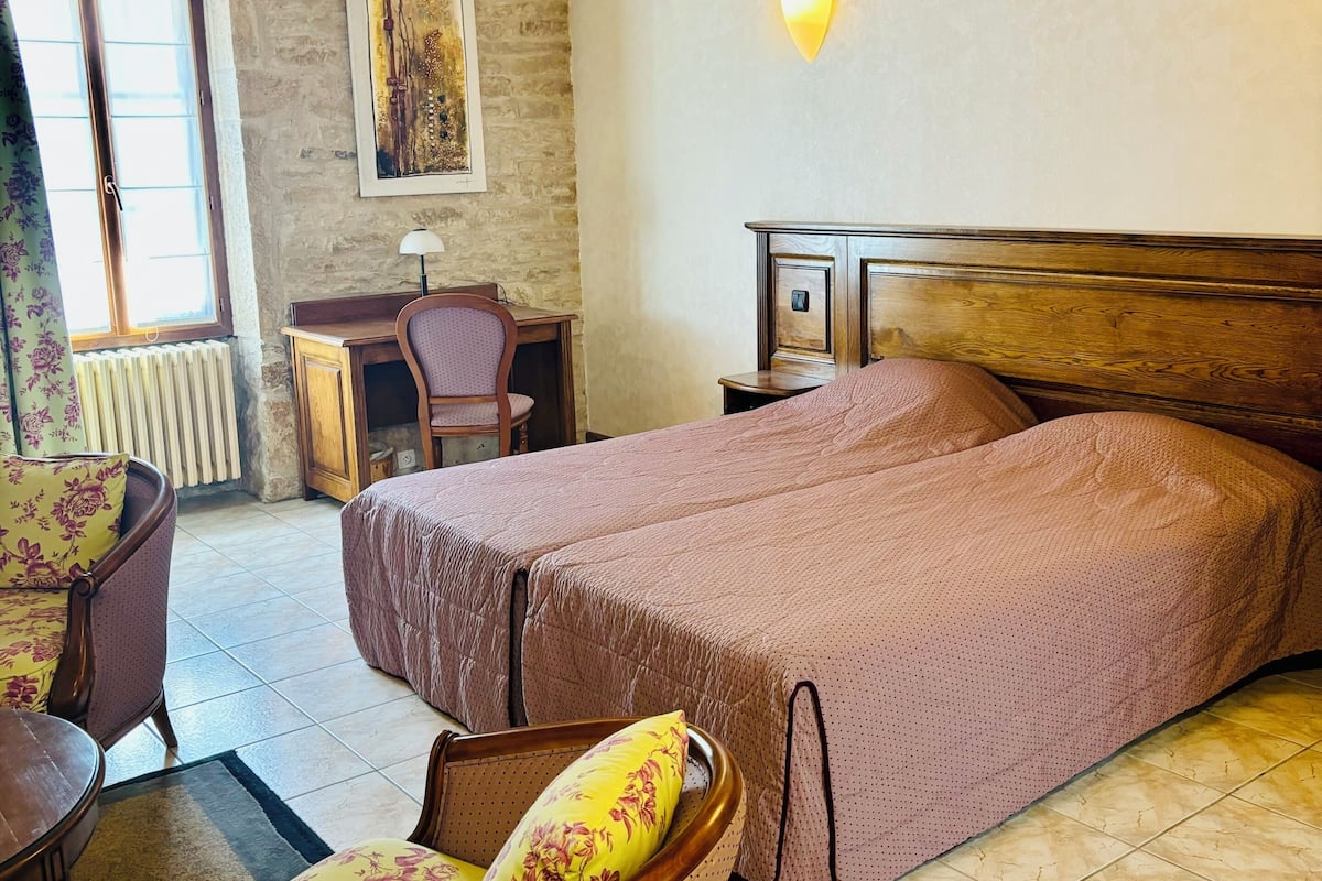 A bedroom with a bed, a chair, a desk, and a lamp.