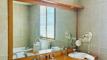 Een badkamer met twee wastafels, een grote spiegel en haardroger bevestigd aan de muur.