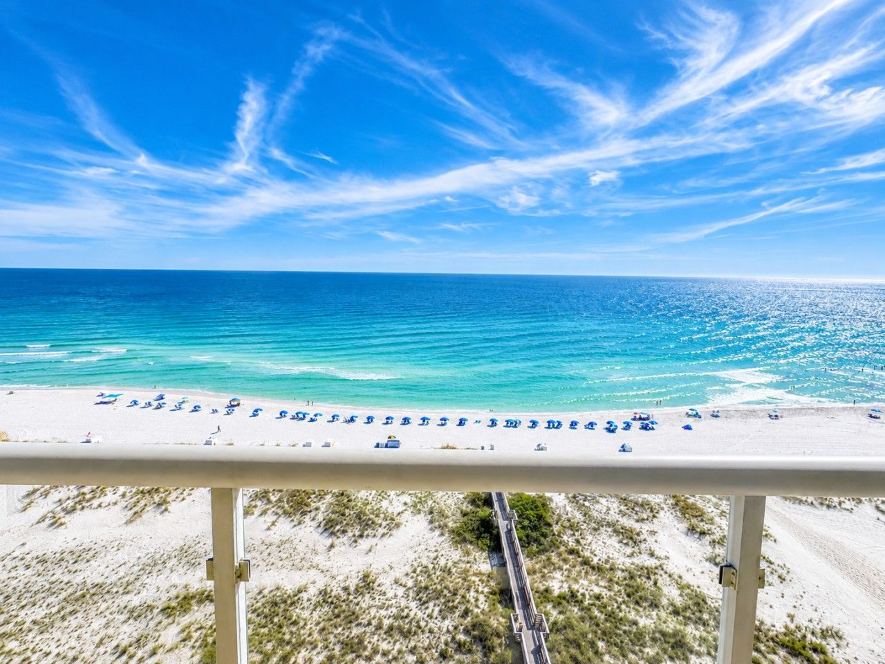 A beach with a clear sky, a sandy shore, and a road leading to the beach.