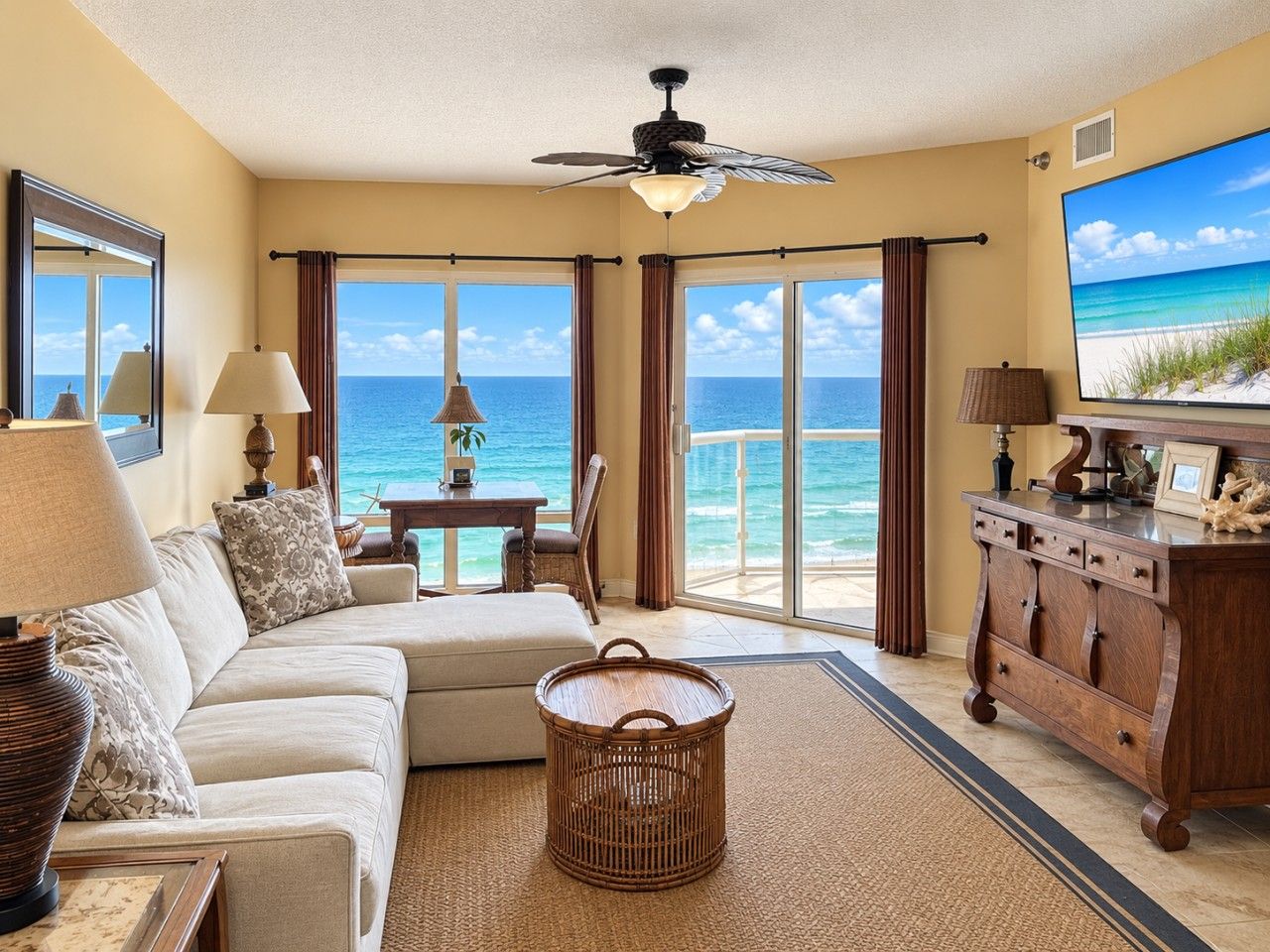 A living room with a sofa, a coffee table, a television, and a view of the ocean.