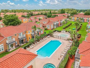 Zona residencial con piscina rodeada de sillas de descanso y una fuente.