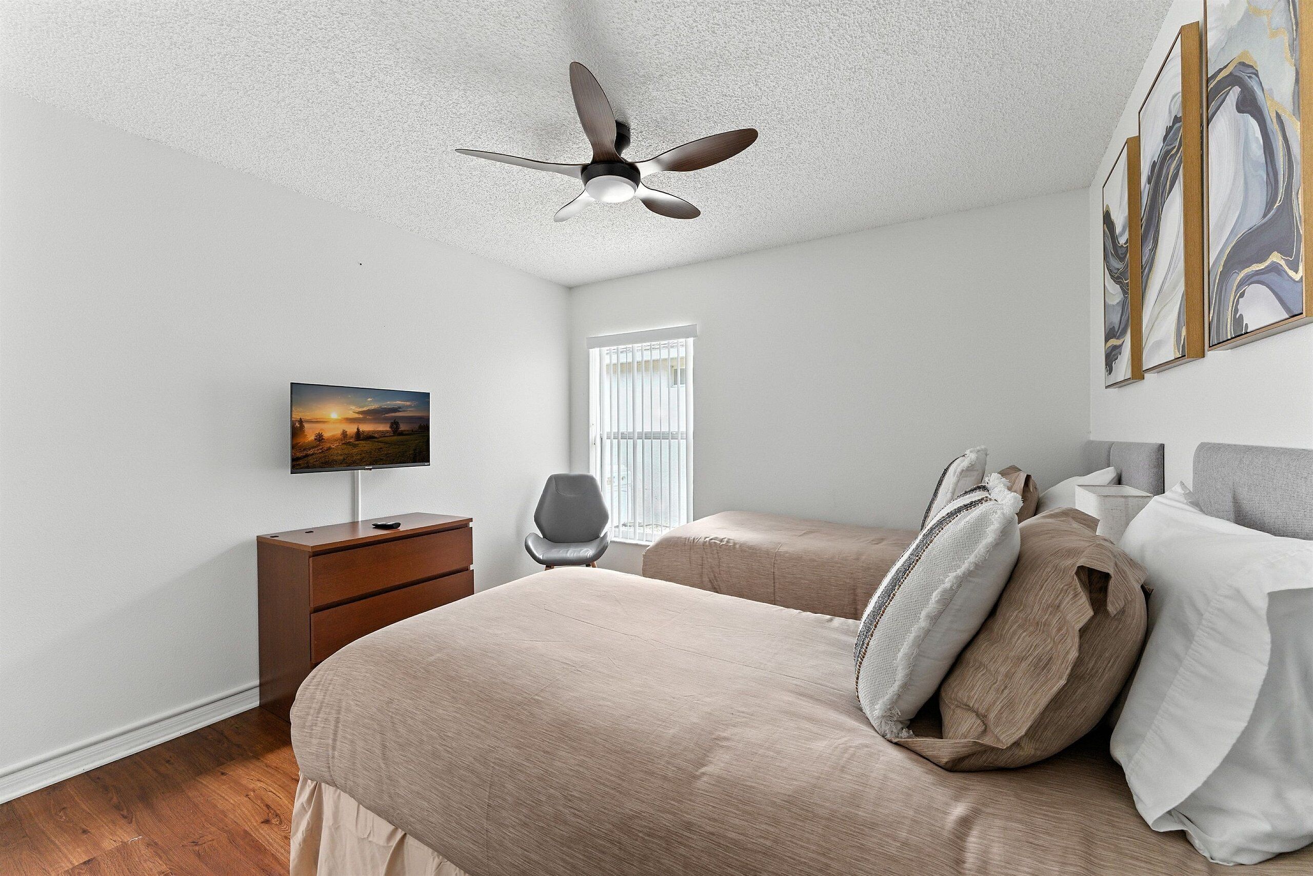 A bedroom with a bed, a TV, a desk, and a chair.