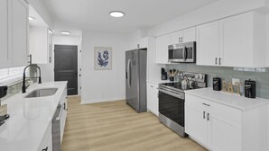 A modern kitchen with white cabinetry, stainless steel appliances, and a wooden floor. - Millersport: The Summit (Millersport)