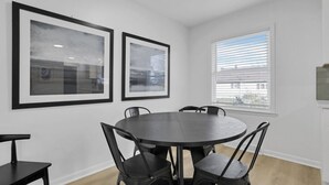 A dining area with a round table and six chairs, framed artwork on the wall, and a window with blinds. - Millersport: The Summit (Millersport)