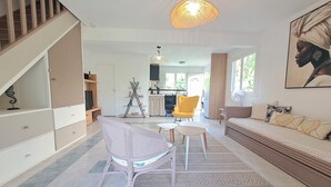 En rummelig opholdsstue med trappe, spisebord og sofa.