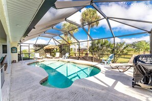 Una piscina exterior techada con sillas de descanso y una parrilla.