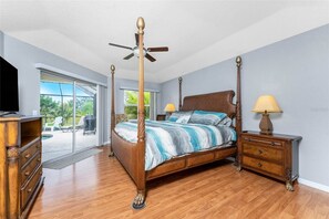Una cama con dosel de madera, una mesita de noche con lámpara y un televisor sobre un aparador.