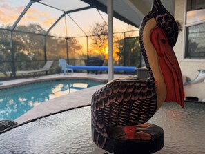 Vista sulla piscina con una scultura a forma di uccello decorativo, la piscina stessa e un'area coperta con lettini.