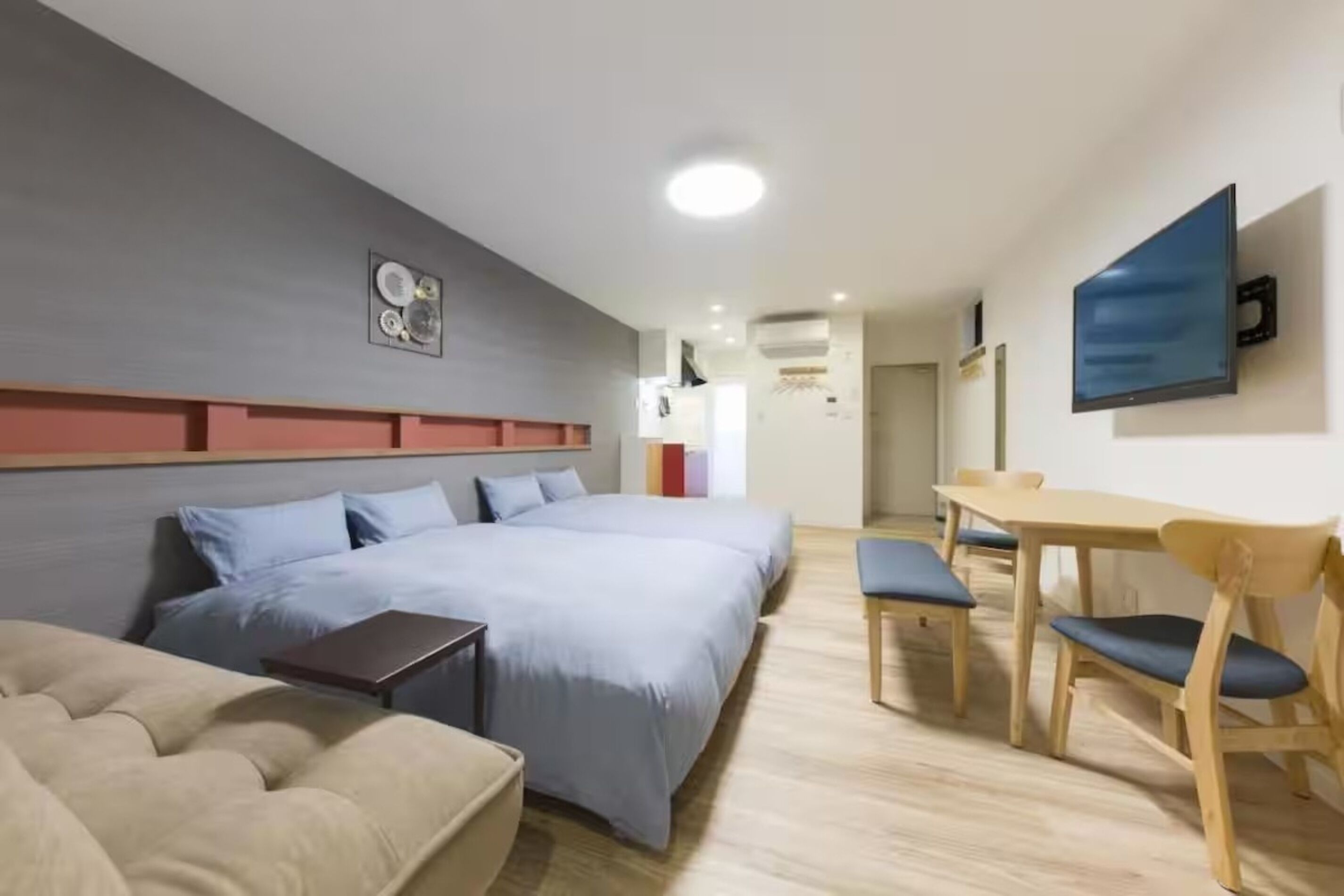 A modern hotel room with a large bed, a desk, and a dining area.