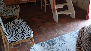 A room with a wooden staircase, a zebra-patterned chair, a cabinet, and a radiator. - Room in thatched cottage in the countryside 2 kms from pointe de la torche (Penmarch)