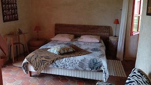 A bedroom with a bed, a chair, a small table, and a window. - Room in thatched cottage in the countryside 2 kms from pointe de la torche (Penmarch)