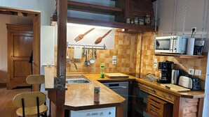 A compact kitchen with wooden cabinets, a built-in microwave, and a coffee maker. - 40-square-meter apartment very close to downtown, 40 minutes from Paris Montparnasse (Épernon)