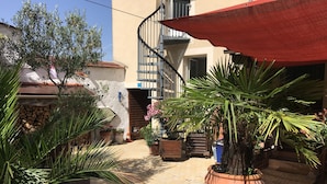 A courtyard with potted plants, a red awning, and a staircase leading to an upper level. - 40-square-meter apartment very close to downtown, 40 minutes from Paris Montparnasse (Épernon)