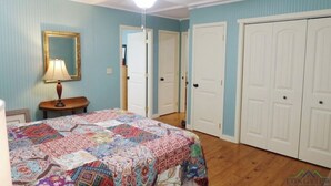 A bedroom with a bed, a ceiling fan, a lamp, and two doors. -  Persimmon Place cozy cabin with AC in Marshall - Perfect for a relaxing getaway (Marshall)