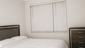 Una camera da letto con un letto, una cassettiera e una finestra con persiane.
