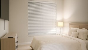Una camera da letto con un letto, un comodino, una lampada e un televisore montato a parete.
