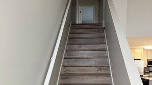 Una escalera de madera con barandillas blancas que lleva a una puerta.