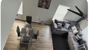 Una sala de estar moderna con una mesa de comedor, sillas, un sofá y un ventilador de techo.