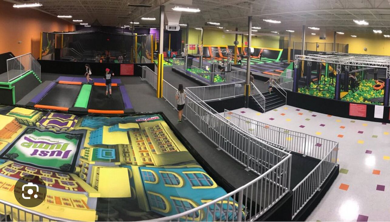 An indoor trampoline park with various play areas and a central platform.