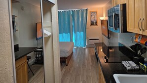 A compact kitchen with wooden cabinets, a microwave, a stove, and a sink. - 10th Fl Inn on the Park | Pool | AC | City & Park View (Honolulu)