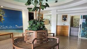 Eine Lobby mit einer Holzbank, einem Blumentopf und einem großen Wandgemälde.
