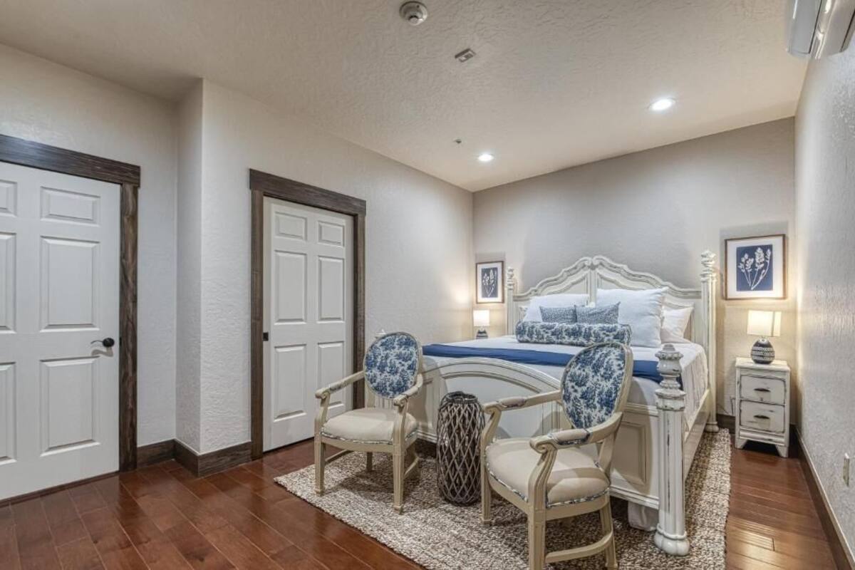 A bedroom with a bed, two chairs, a nightstand, and a rug.