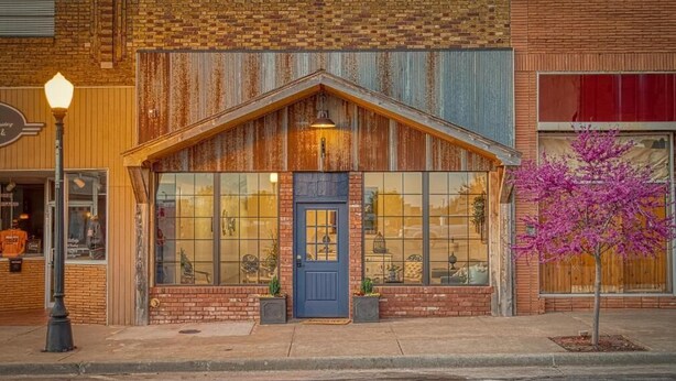 A building with a prominent wooden facade, a blue door, and large windows. - Bluebird Place (Elk City)
