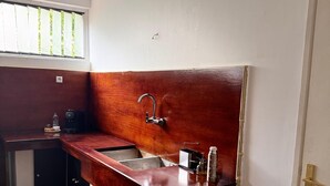 Eine kleine Küche mit Holzarbeitsplatte, einem Einzelwaschbecken und einem Fenster mit Jalousien.